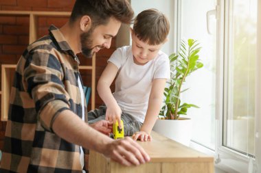 Evde mobilya ölçüleri alan baba ve oğul.