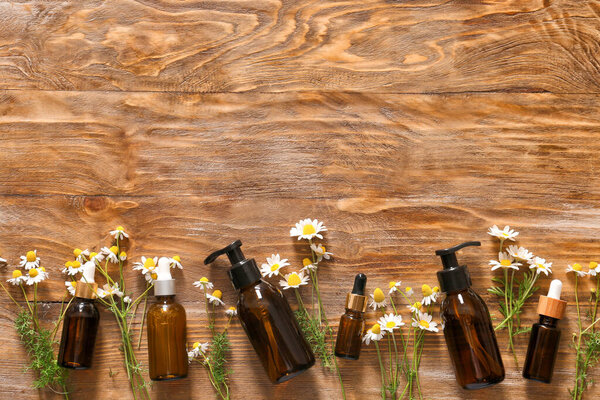 Cosmetics with chamomile flowers on wooden background