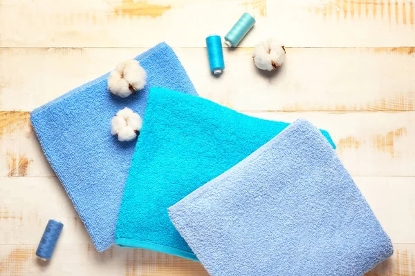 Cotton flowers, threads and soft towels on wooden background