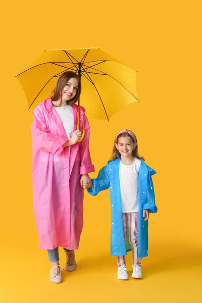 stock image Mother and little daughter with umbrella on color background