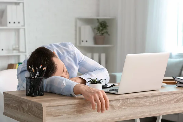 Young man falling asleep during work in office. Concept of sleep deprivation