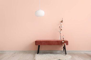 Renkli duvarın yanında pamuk çiçekli şık bir bank.