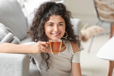 Güzel genç bayan evde sıcak çay içiyor.