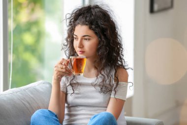 Güzel genç bayan evde sıcak çay içiyor.