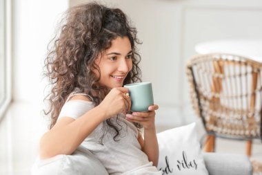 Güzel genç bayan evde sıcak çay içiyor.