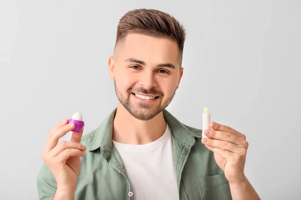 Joven Guapo Con Bálsamos Labiales Sobre Fondo Claro —  Fotos de Stock