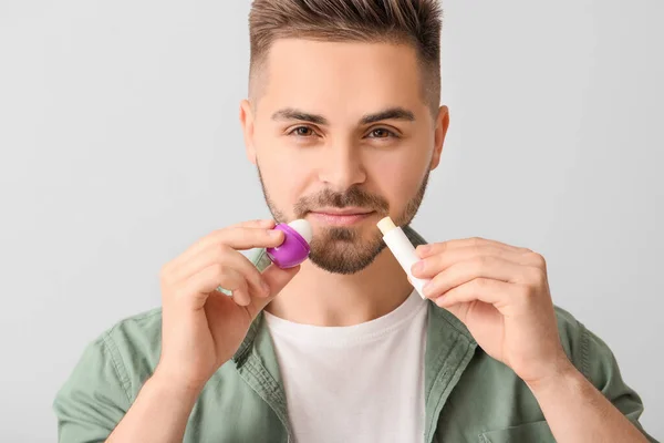 Schöner Junger Mann Mit Lippenbalsam Auf Hellem Hintergrund — Stockfoto