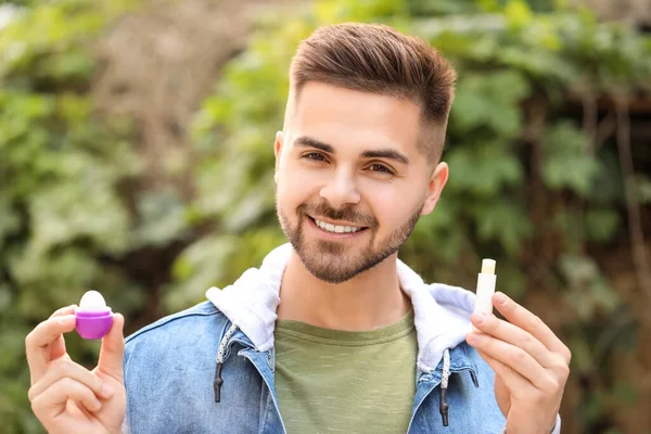 Handsome young man with lip balms outdoors