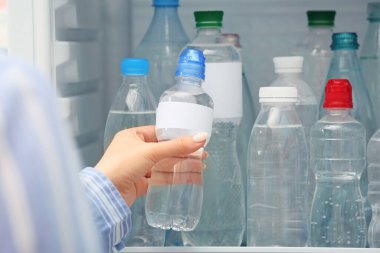 Bir kadın dükkandaki buzdolabından su alıyor.