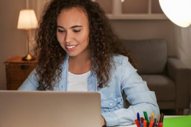 Evde online öğrenim için dizüstü bilgisayar kullanan genç bir kadın