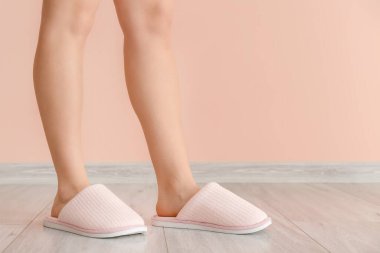 Evde yumuşak terlikli bir kadın var.