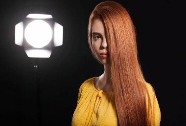 Koyu arkaplanda güzel kızıl saçlı bir kadın.