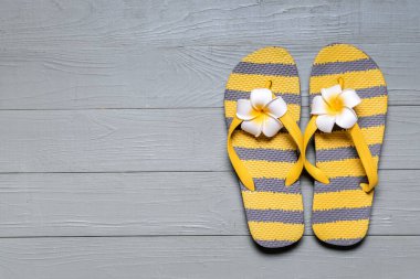 Ahşap arka planda şık parmak arası terlikler