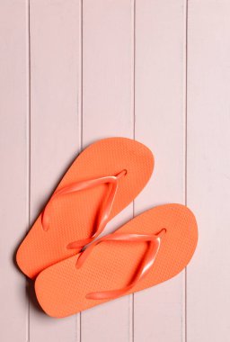 Ahşap arka planda şık parmak arası terlikler