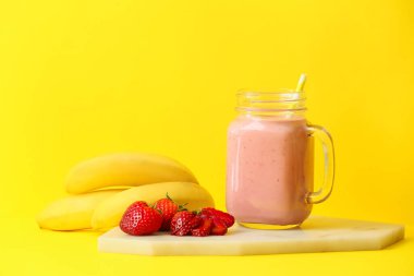 Mason kavanozu renkli arkaplanda lezzetli çilekli smoothie.