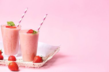 Renkli arkaplanda lezzetli çilekli smoothie bardakları