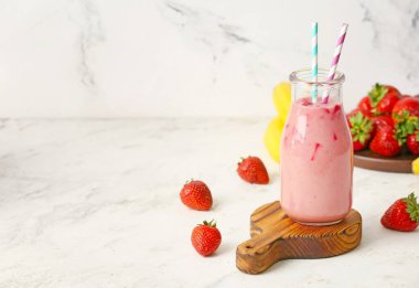 Beyaz arka planda bir şişe lezzetli çilekli smoothie.