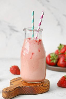 Beyaz arka planda bir şişe lezzetli çilekli smoothie.