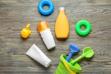 Güneş kremi ve tahta arka planda kumsal oyuncakları.