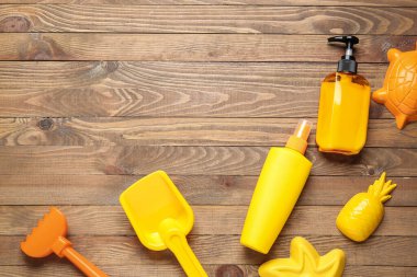 Güneş kremi ve tahta arka planda kumsal oyuncakları.