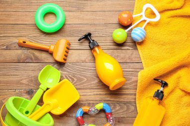 Plaj oyuncaklarıyla güneş kremi ve ahşap arka planda havlu.