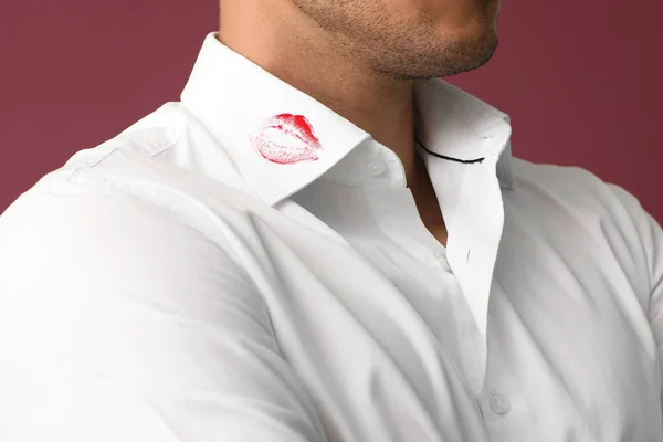 Young businessman with lips print on shirt collar against color background, closeup