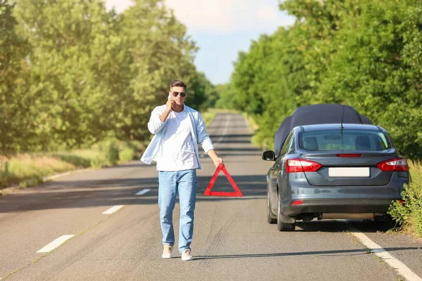 Молодий Чоловік Знаком Аварійної Зупинки Біля Розбитого Автомобіля Дорозі — стокове фото