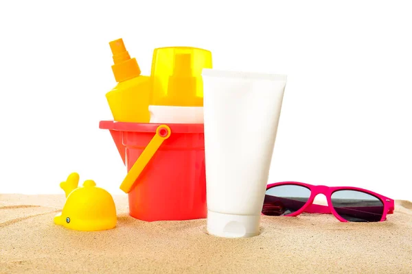 白い背景にビーチの砂のおもちゃやサングラスと日焼け止めクリーム — ストック写真