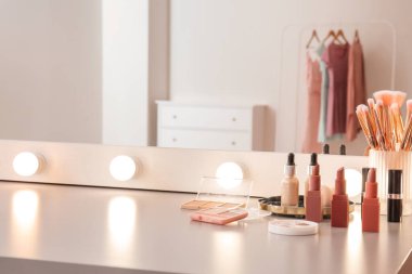 Modern makyaj odasında dekoratif kozmetik ve ayna olan masa.