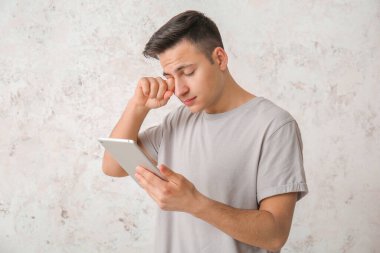 Arka planda tablet bilgisayarı olan yorgun bir adam. Uykusuzluk kavramı