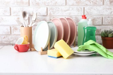 Mutfak masasında temiz bulaşık ve deterjan var.