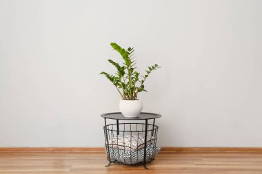 Odadaki ışık duvarının yanında çiçekli ve yumuşak yastıklı masa.