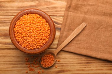 Ahşap zemin üzerinde kırmızı mercimek olan kase ve kaşık