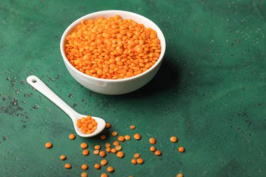 Arka planda kırmızı mercimek olan kase ve kaşık