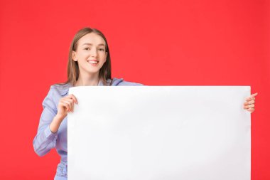 Arkaplanda boş posteri olan genç bir kadın.