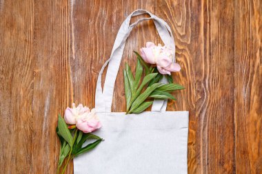 Ahşap zemin üzerinde çiçekler olan bir çanta.