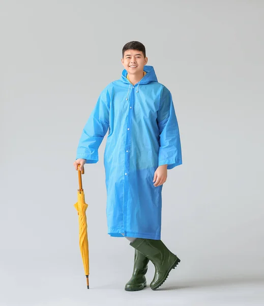 Yağmurluklu Gri Arka Planda Şemsiyesi Olan Asyalı Genç Bir Adam — Stok fotoğraf