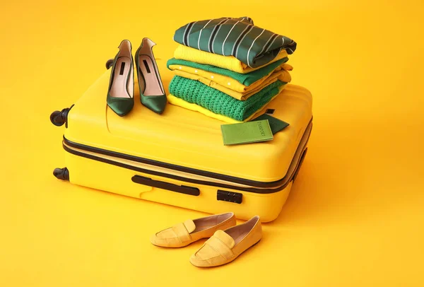 stock image Suitcase with travel accessories on color background