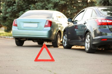 Yolda kaza yaptıktan sonra kırık arabaların yanında dur işareti var.