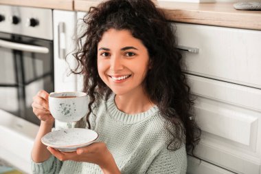 Güzel genç bayan evde sıcak çay içiyor.