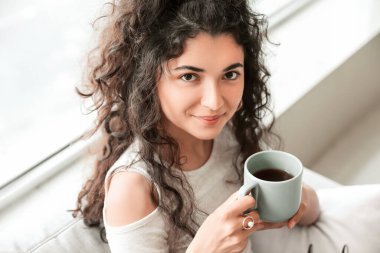 Güzel genç bayan evde sıcak çay içiyor.