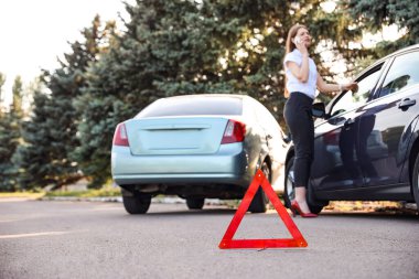 Yolda kaza yaptıktan sonra kırık arabaların yanında dur işareti var.