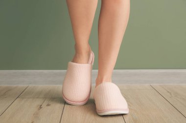 Evde yumuşak terlikli bir kadın var.