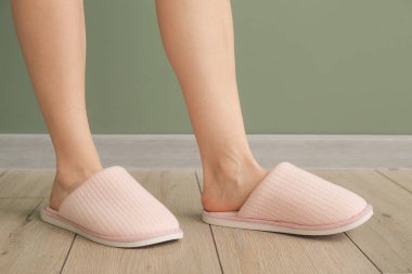 Evde yumuşak terlikli bir kadın var.