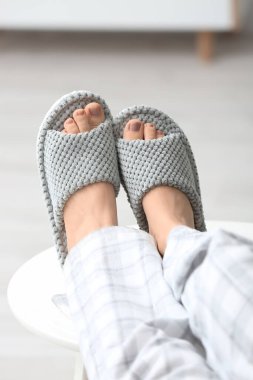 Evde yumuşak terlikli bir kadın var.