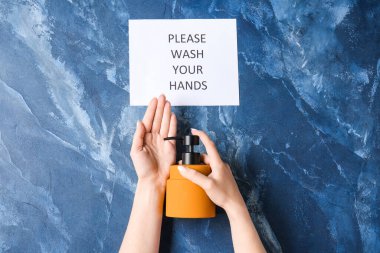 Lütfen mesajlaşın. Ellerinizi yıkayın ve kadının eline sıvı sabun sürün. Renk arkaplanı, üst görünüm