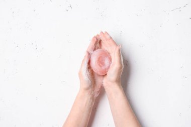 Beyaz arka planda sabunla ellerini yıkayan kadın.