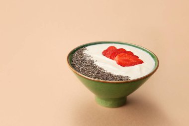 Arka planda bir kase sağlıklı çilekli yoğurt.