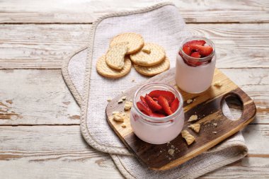 Masada sağlıklı çilekli yoğurt kavanozları var.