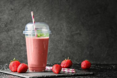 Koyu arkaplanda bir fincan lezzetli çilekli smoothie